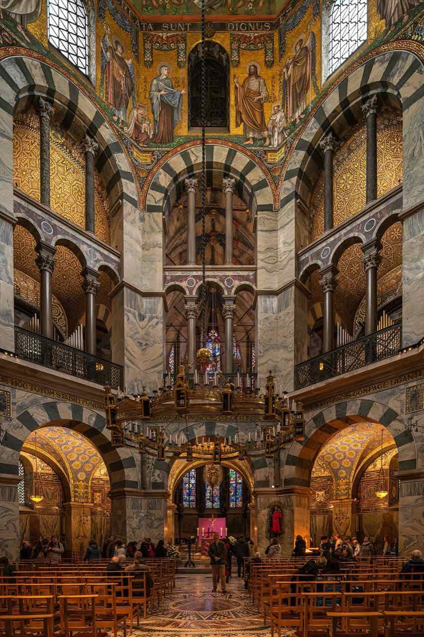 Looking up and along the Carolingian octagon of Aachen Cathedral with the large Barbarossa chandelier and gold mosaics