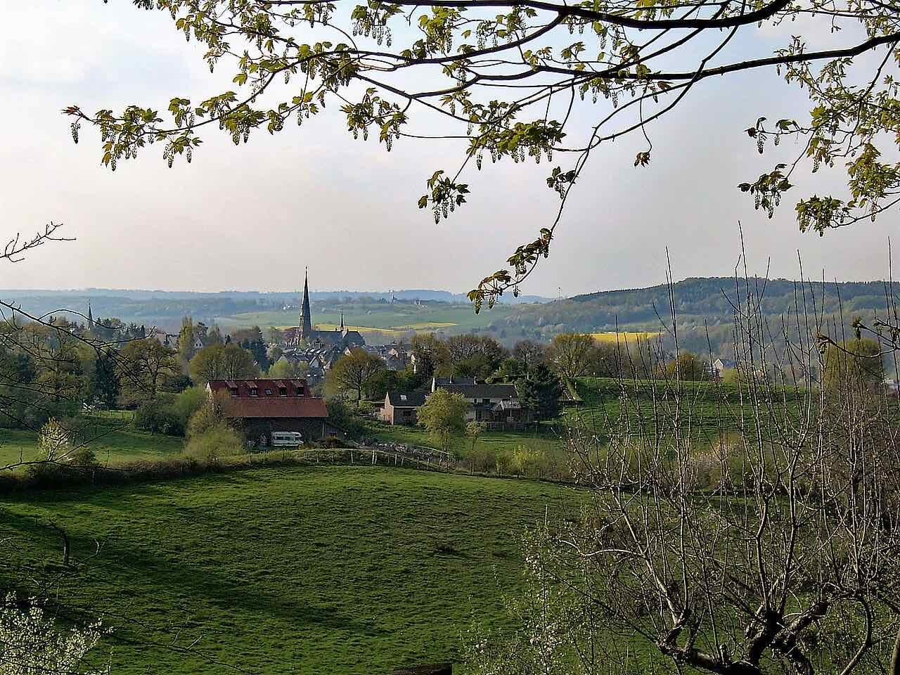 Green fields and the church tower of Vaals in the Netherlands, seen through branches from the tripoint hill