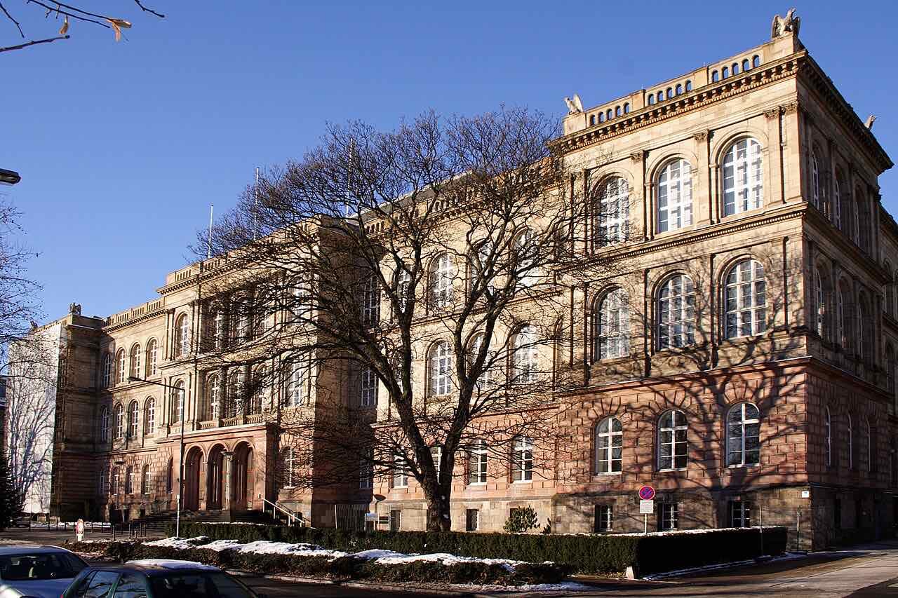 The sandstone main building of RWTH Aachen with arched windows on a sunny winter day