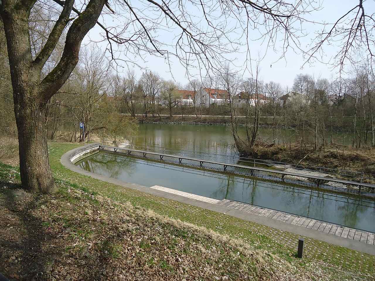 The point where the Eiskanal leaves the river Lech, with a long still basin, a walkway and bare trees in early spring