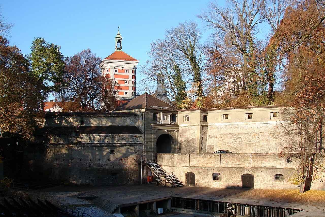 The Rotes Tor gate in the old town wall with its red and white tower, seen over the open-air stage in the moat on an autumn day