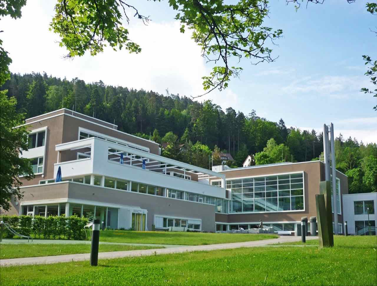 The modern building of the Paracelsus-Therme with a forested hill behind it