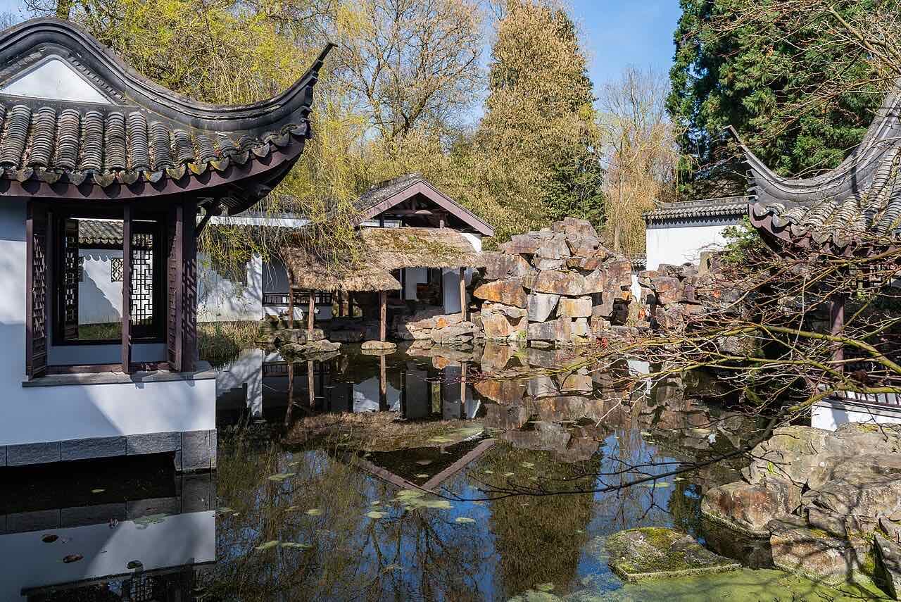 The Chinese garden in the Botanical Garden of Ruhr University Bochum, with curved roofs and a pond reflecting rocks and trees