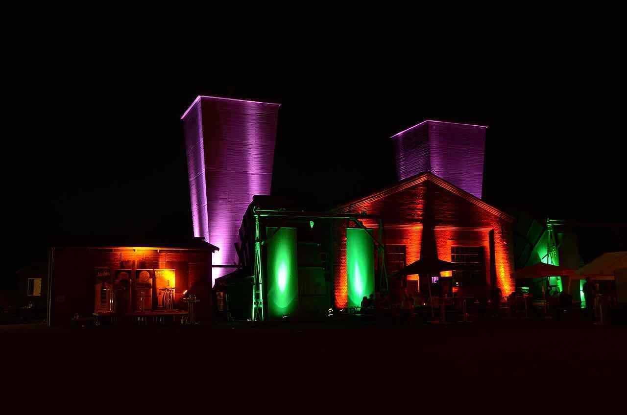 The two tapering ventilation buildings of Zeche Hannover lit in purple and green at night