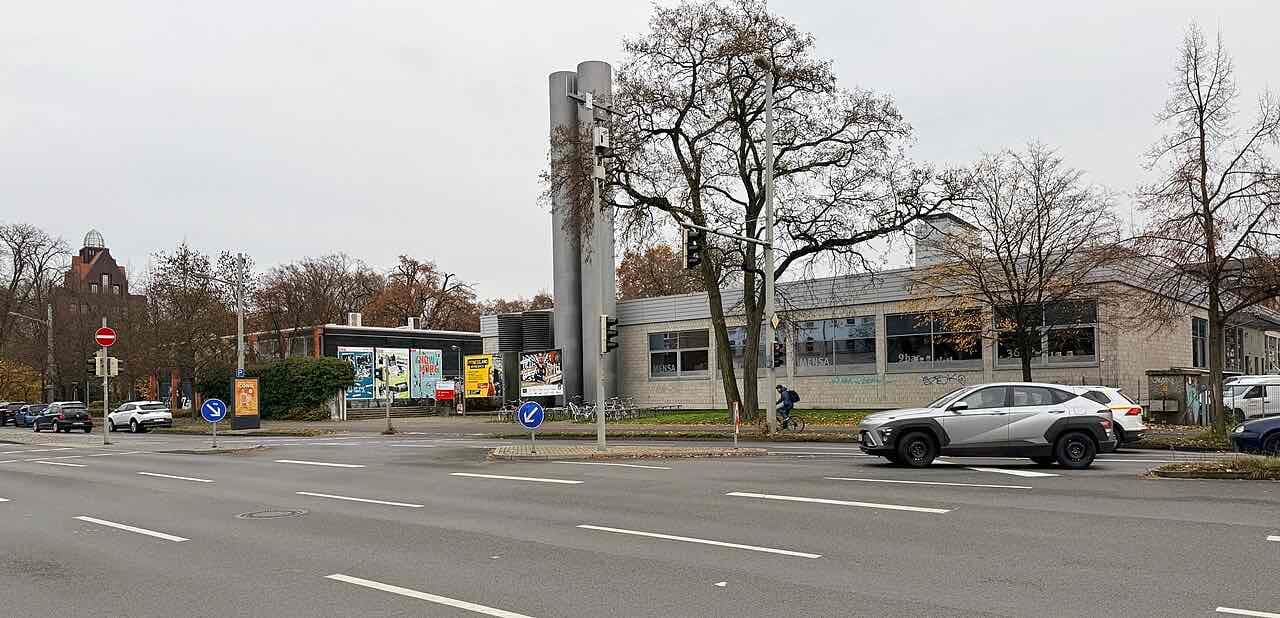 The low Mensa 1 building of the TU on Katharinenstraße behind a busy road, with bare trees and a brick tower in the background