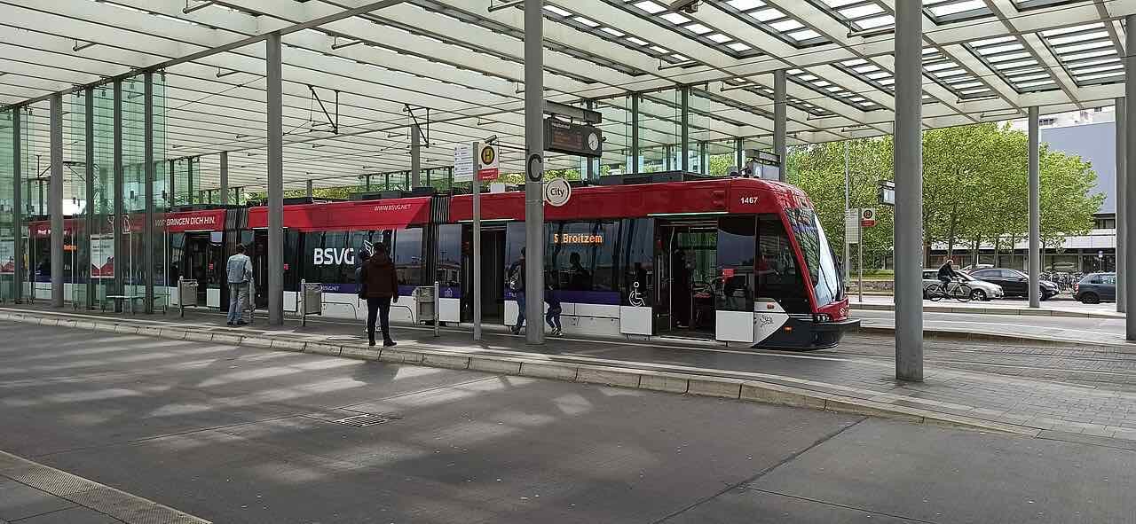 A red and white BSVG tram waiting under the glass canopy of the stop at the Hauptbahnhof