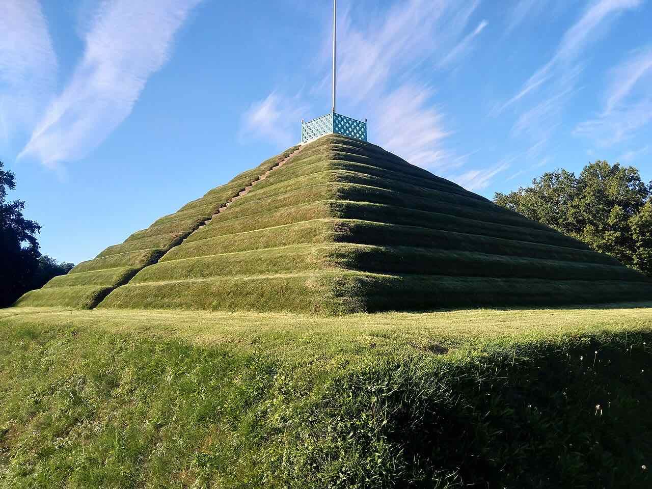 The grass-covered stepped Land Pyramid in the Branitz park with a flagpole and a small lattice platform on top