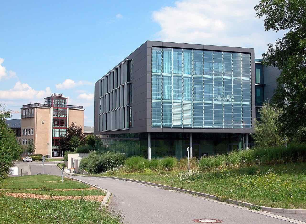 A glass-fronted faculty building of TU Dresden in the south of the city, with a older brick building beside it and lawns in front