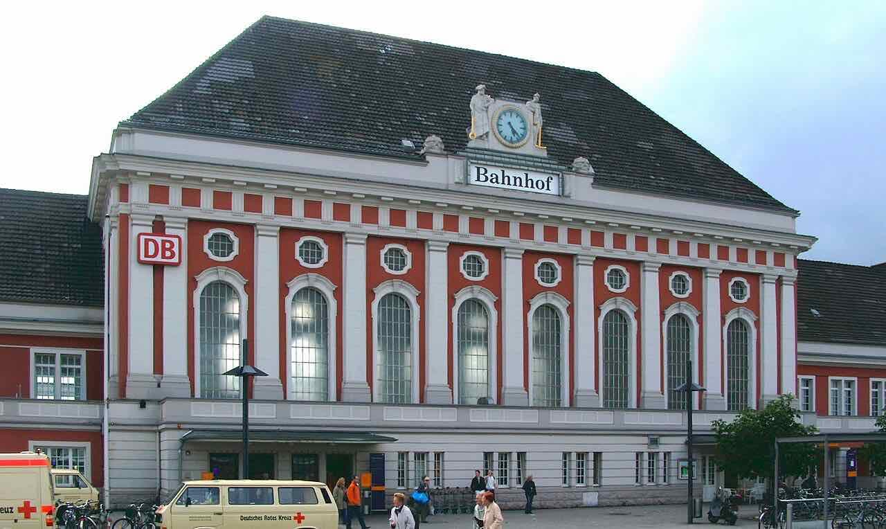 The front of Hamm central station: a red and white classical building with tall arched windows and a clock under the roof