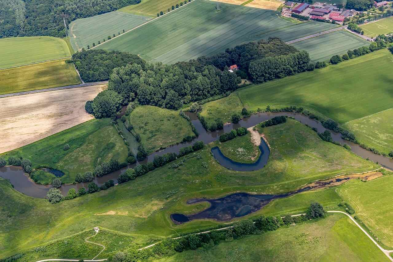 Aerial view of the Lippe meadows: a winding river, oxbow ponds, woodland and fields in several greens
