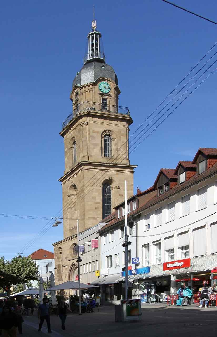 The Hafenmarktturm in Heilbronn, a sandstone tower with a clock and a slate roof, rising above a pedestrian shopping street