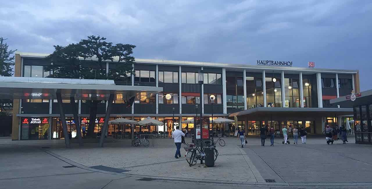 The front of Hildesheim main station in the evening, with a bike stand and people crossing the forecourt