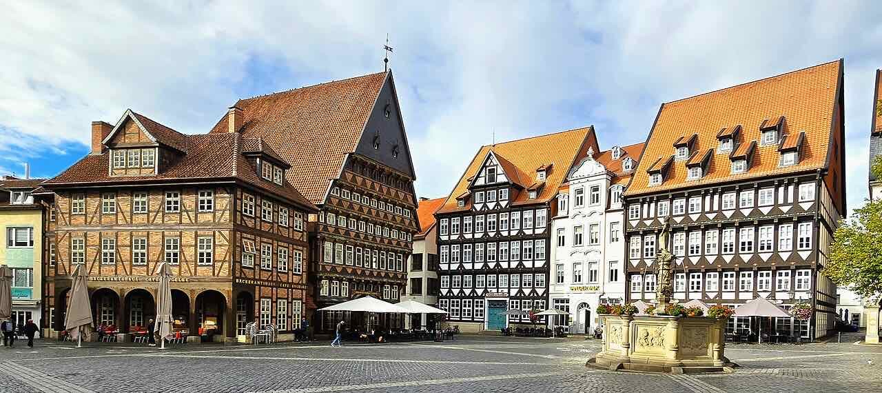 The Hildesheim market square with the half-timbered Knochenhaueramtshaus, white and timbered gabled houses and the fountain on the right under a cloudy sky