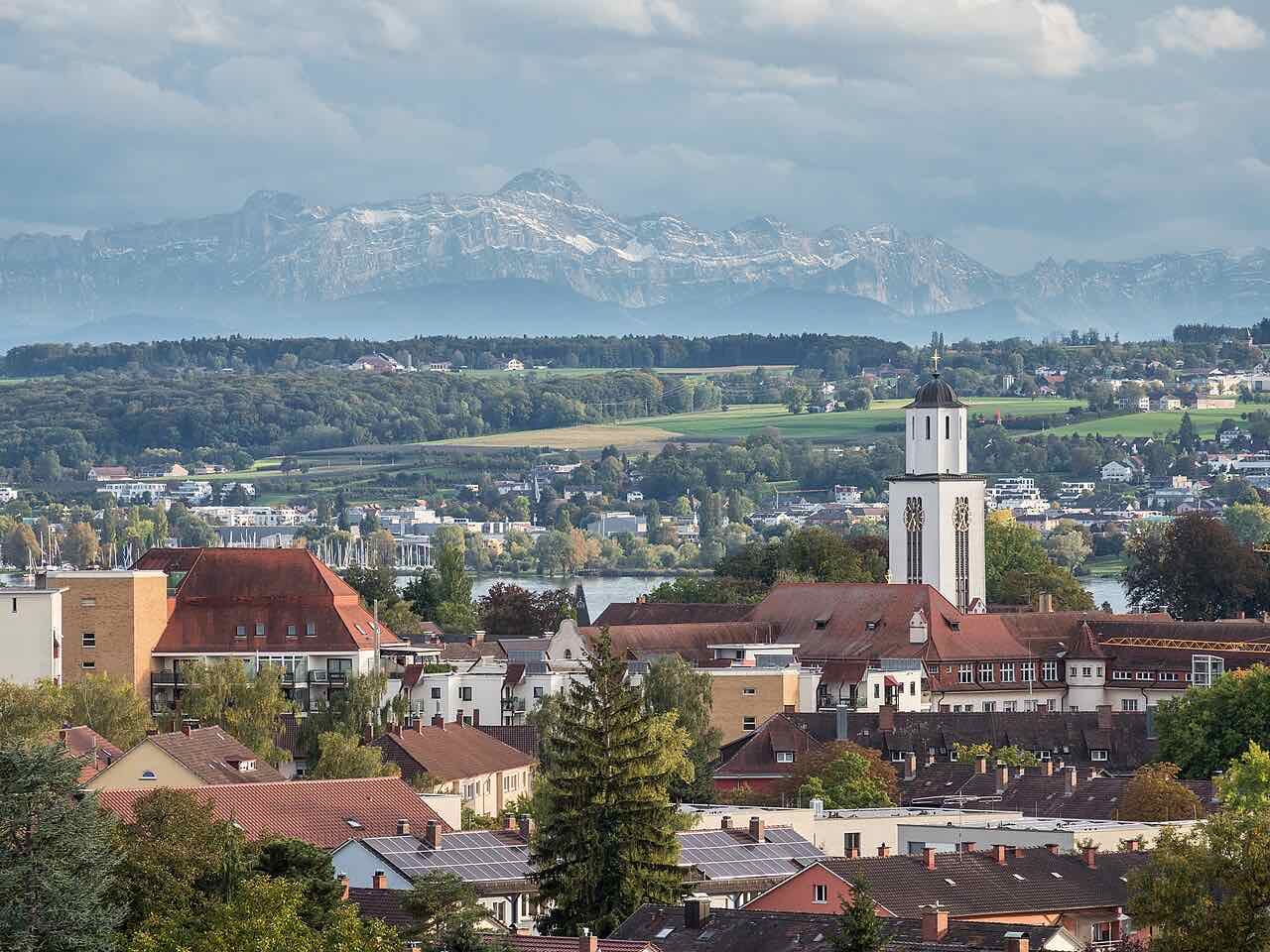 Red roofs and a white church tower in Konstanz with the lake behind and the snowy Alpstein mountains on the horizon