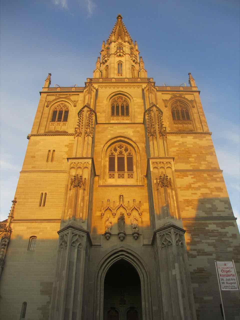 The tall west tower of Konstanz Minster in warm evening light against a blue sky