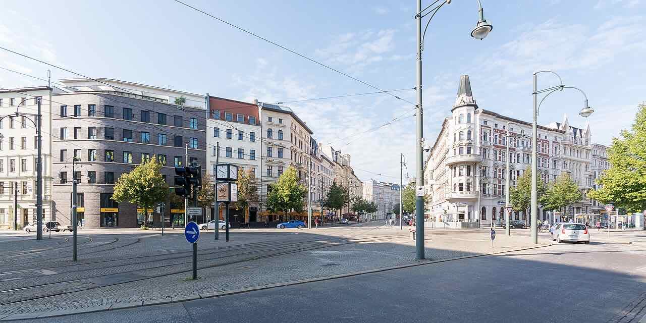 Hasselbachplatz in Magdeburg on a clear day, with tram tracks and old apartment buildings around the square