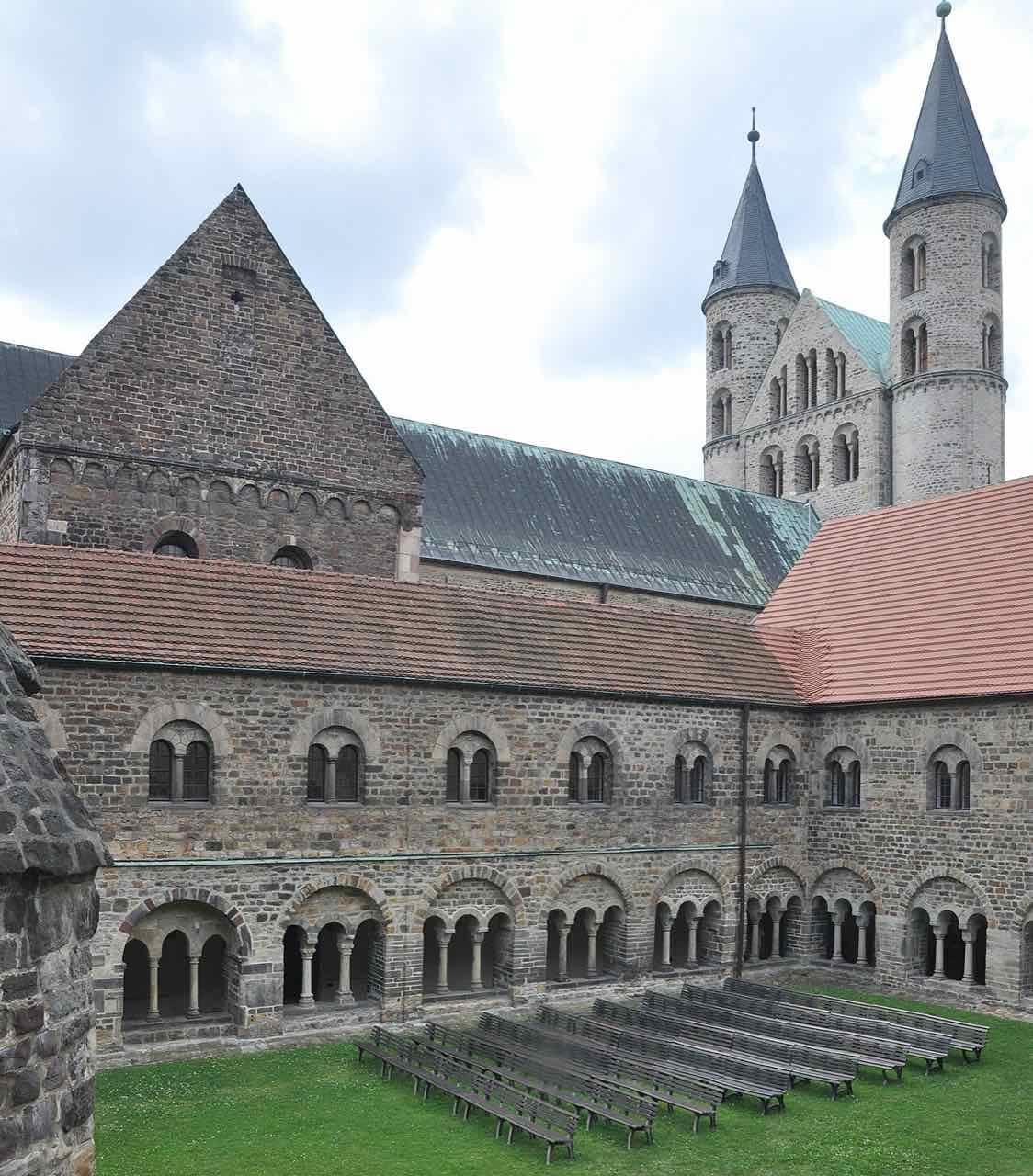 Romanesque cloister and twin towers of Kloster Unser Lieben Frauen with rows of benches on the lawn