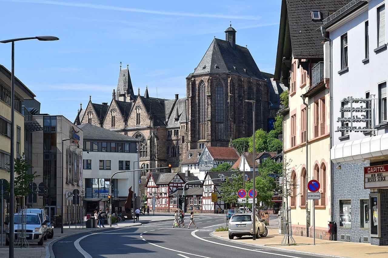 A street in the old town with half-timbered houses and the tall Gothic university church rising behind them on a sunny day