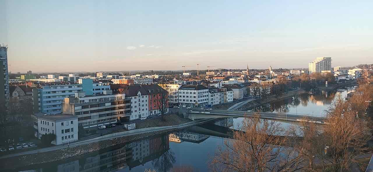 The Neu-Ulm waterfront in early light, with apartment blocks, a road bridge and the river Danube seen from the Ulm side