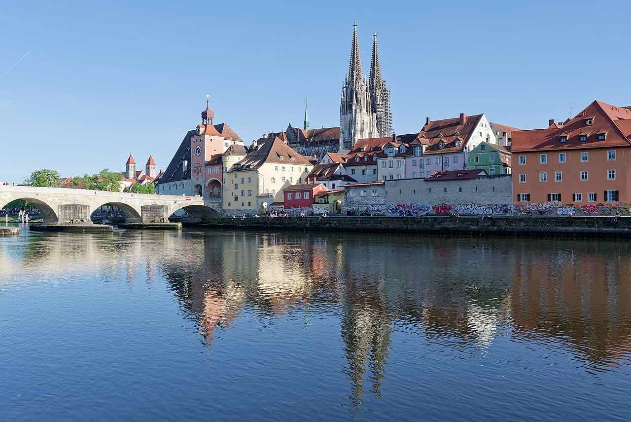 The Stone Bridge, the bridge tower and the two spires of the cathedral seen across the Danube on a clear day, with the old town reflected in the water