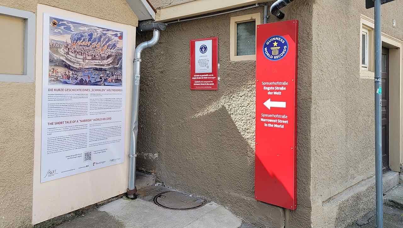 The entrance to the Spreuerhofstraße with a red sign reading Engste Straße der Welt and an information board about the street