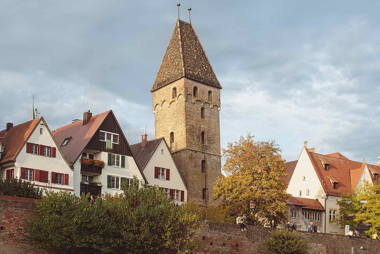 The Metzgerturm, a square brick tower with a tiled roof, rising above half-timbered houses and the old city wall in autumn light