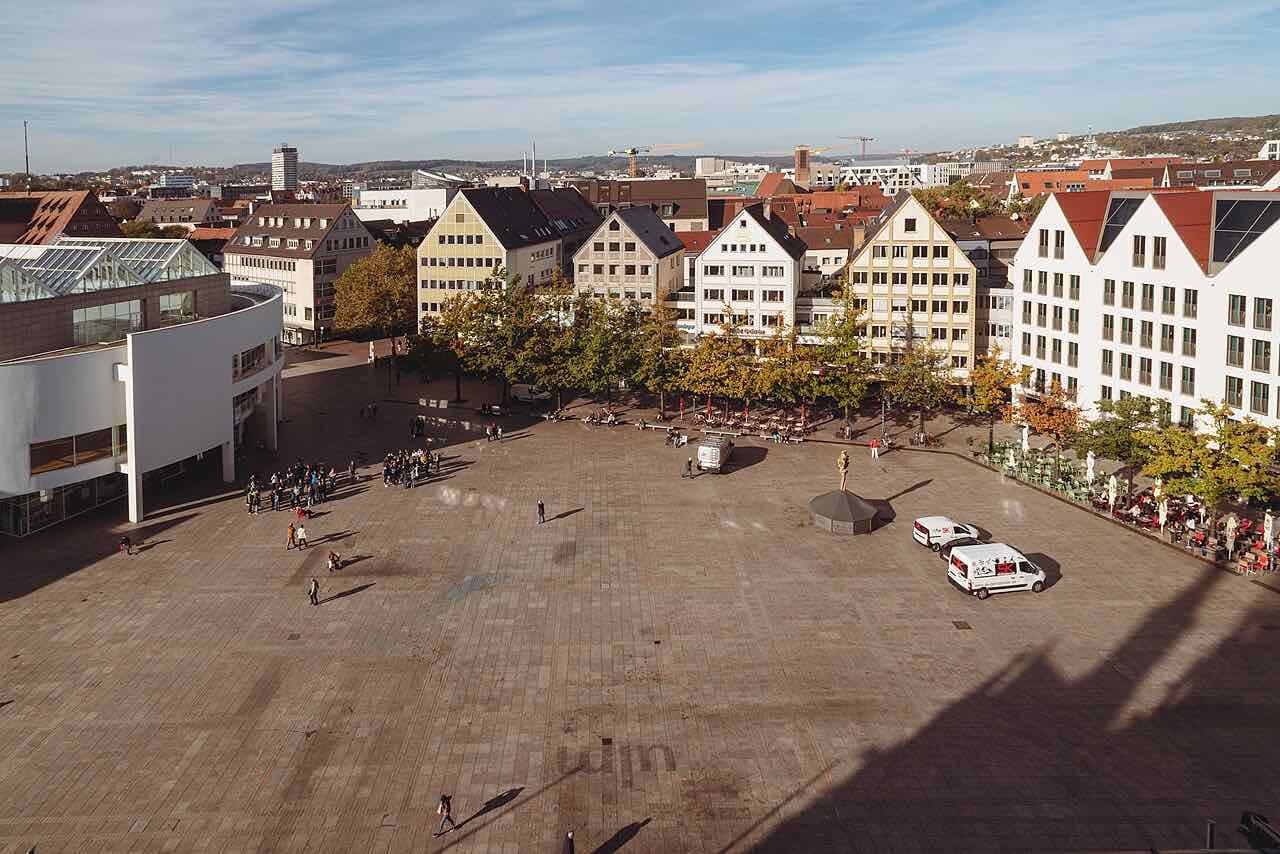 The wide, paved Münsterplatz seen from the Minster tower, with cafe terraces and gabled houses along one side