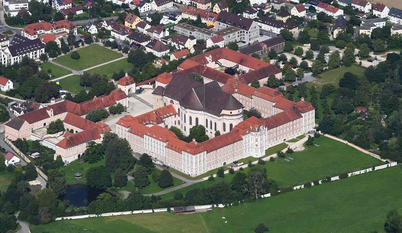 Aerial view of Wiblingen Abbey, a large baroque monastery with red roofs, a domed church and gardens
