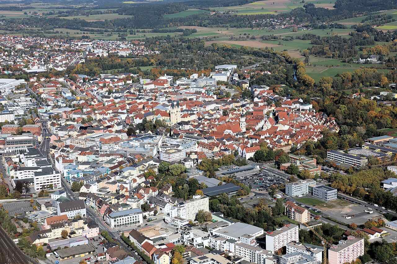 Aerial view of the old town core of Weiden, with red roofs around the market and the church towers