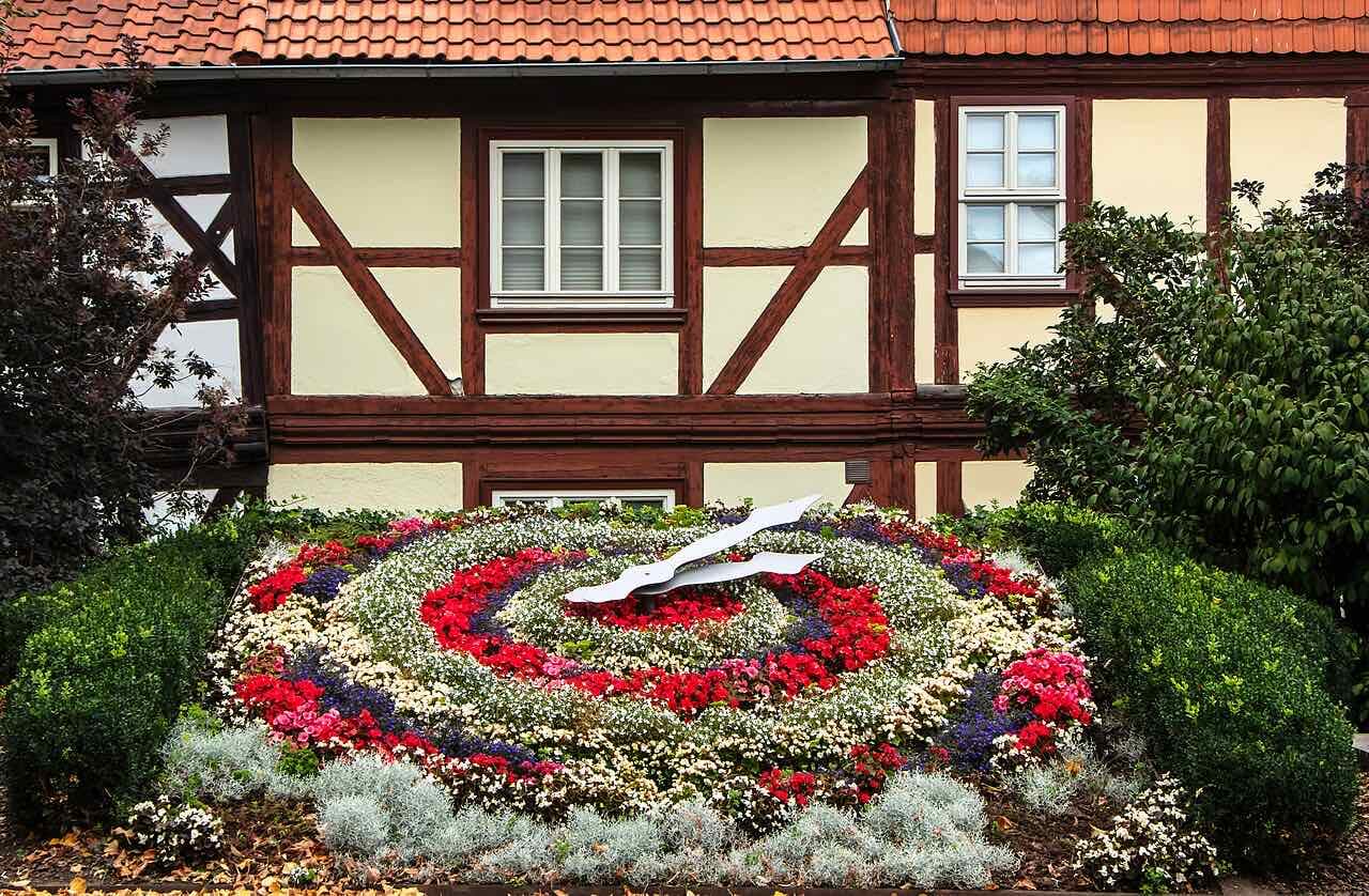 The flower clock behind the town hall in Wernigerode, with trees and half-timbered houses around it