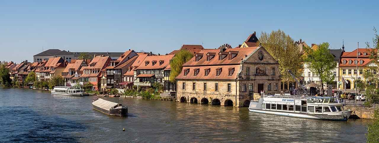 The old fishermen's houses of Klein Venedig along the Regnitz, with a sandstone building on the water and an excursion boat moored at the quay