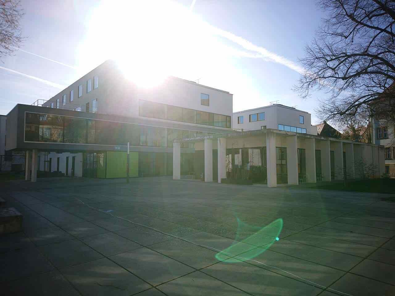 The open paved square of the Markusgelände campus with modern white university buildings behind it
