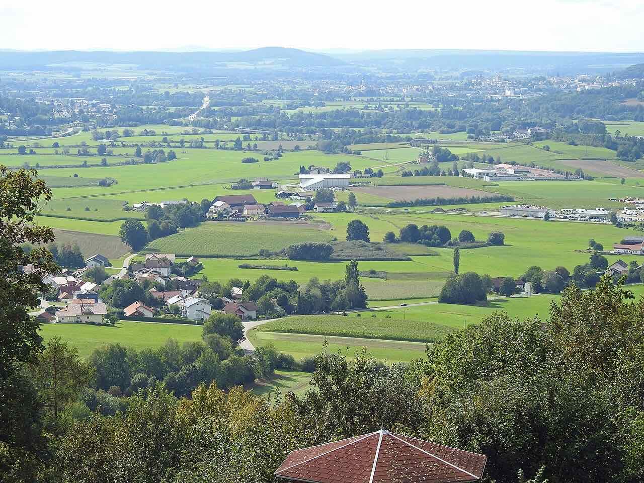 A wide green valley of fields and farms seen from the castle ruin at Runding, with wooded hills far away