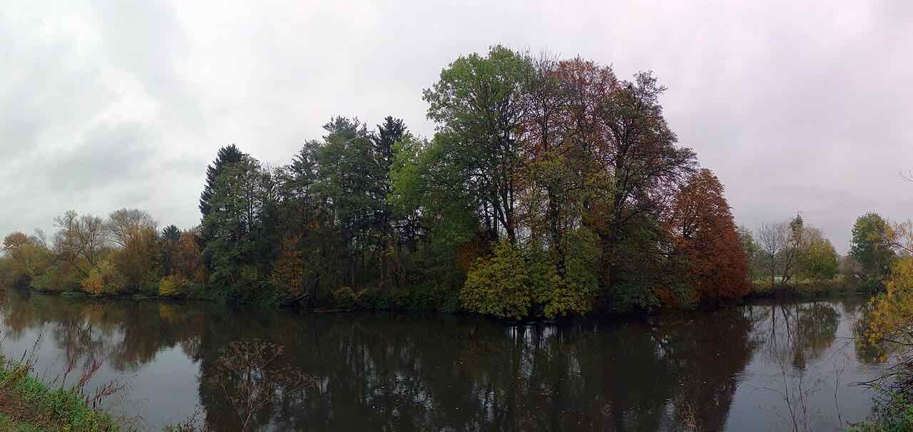 Schmidtsinsel, a wooded island in the river Regnitz in Erlangen, with autumn trees reflected in the water