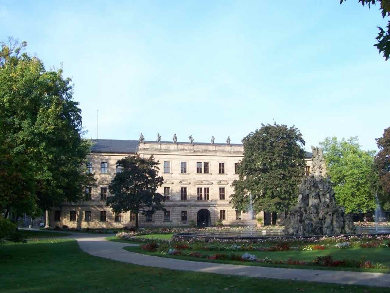 The sandstone palace of Erlangen seen across flower beds and the fountain of the palace garden
