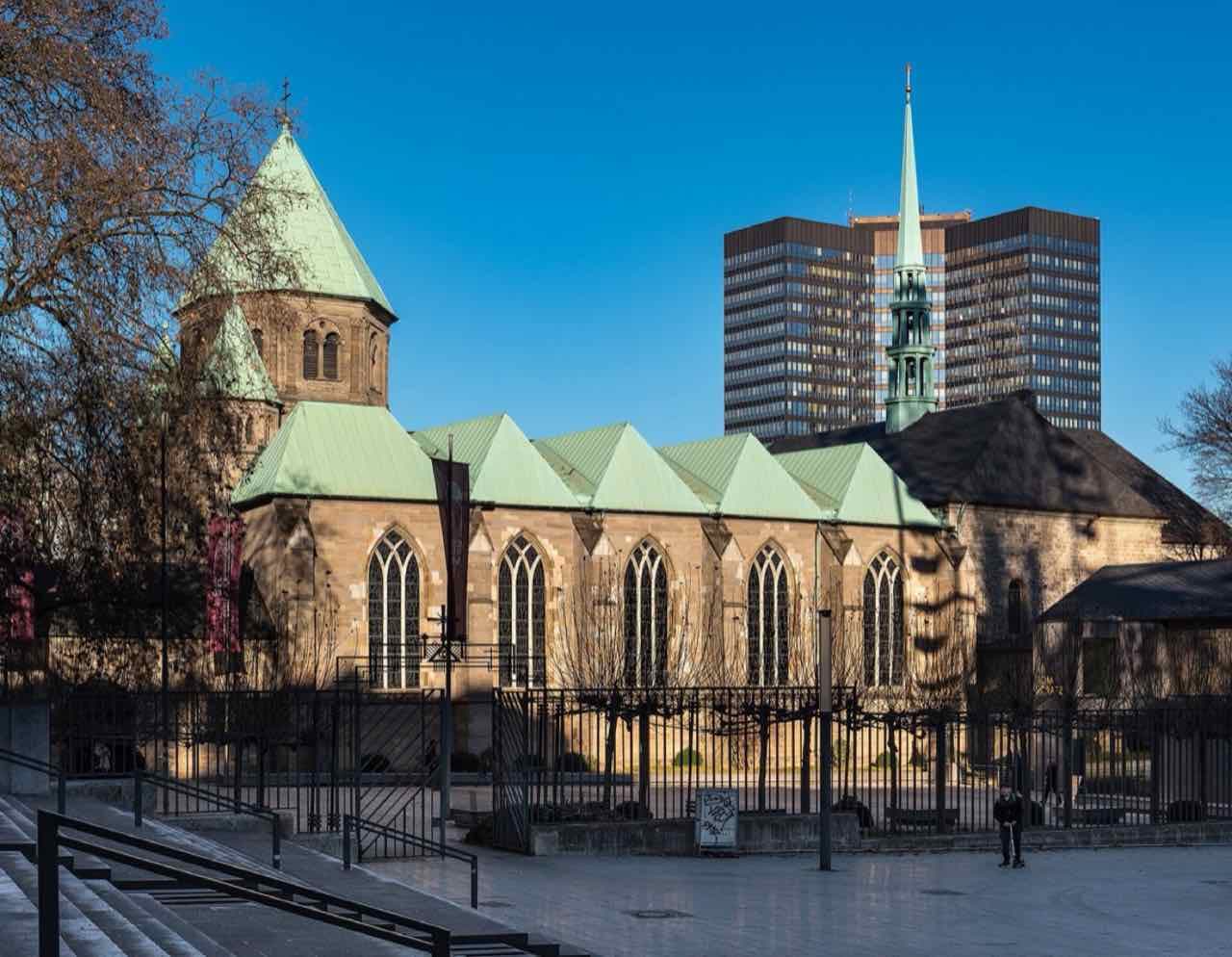 The Essen Cathedral (Münster) with its green copper roofs and a tower block of the town hall behind it on a sunny winter day