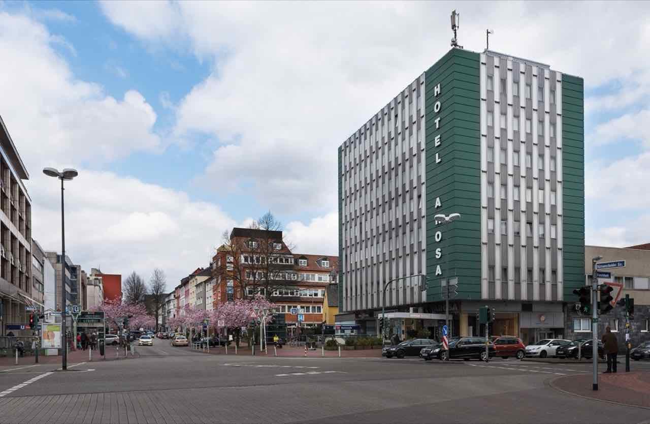 Rüttenscheider Straße in Essen with a green hotel tower, cherry trees in bloom and an underground station sign