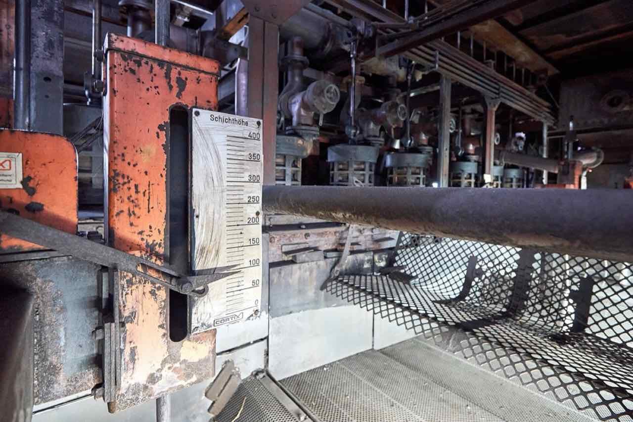 Rusty orange and grey machinery inside the Zollverein coking plant, with a gauge labelled Schichthöhe