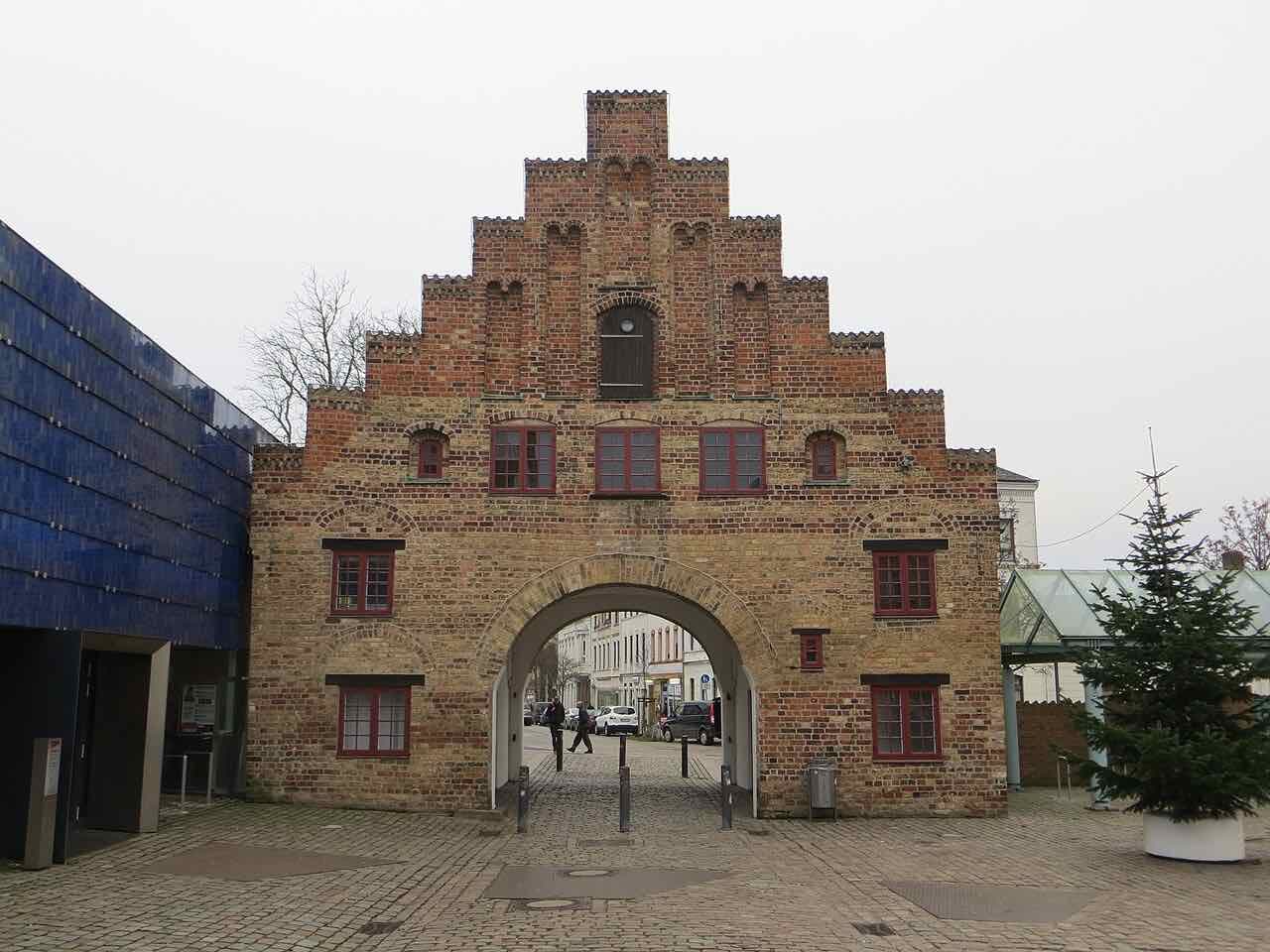 The Nordertor, a stepped-gable brick gateway with an arched passage, on a grey winter day with a small Christmas tree beside it