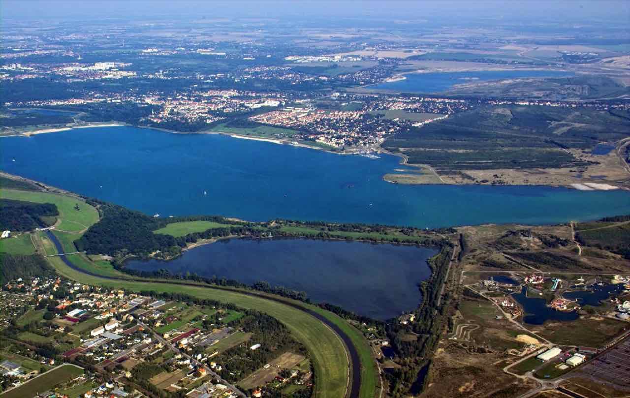 Aerial view of the Cospudener See, a large blue lake with a long sandy shore and a smaller lake in front of it