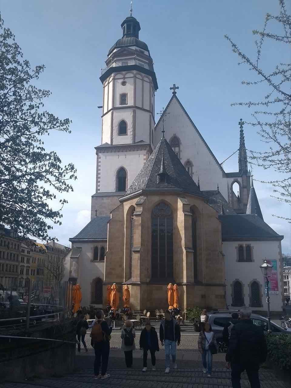 The Thomaskirche seen from the east end, with its white tower, a dark pitched roof and a few people walking in front