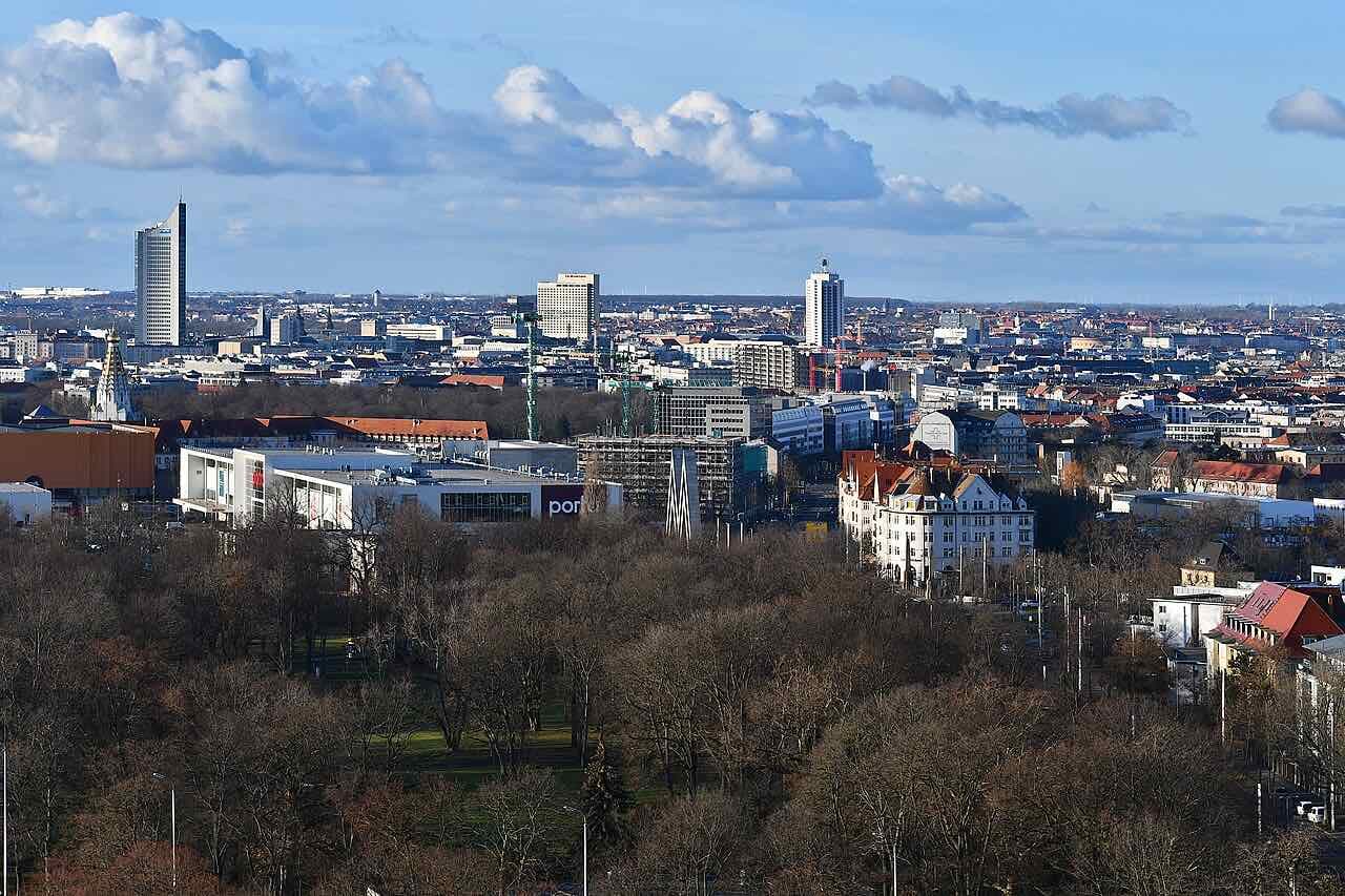 The Leipzig skyline in winter light behind a wooded park, with a tall tower on the left