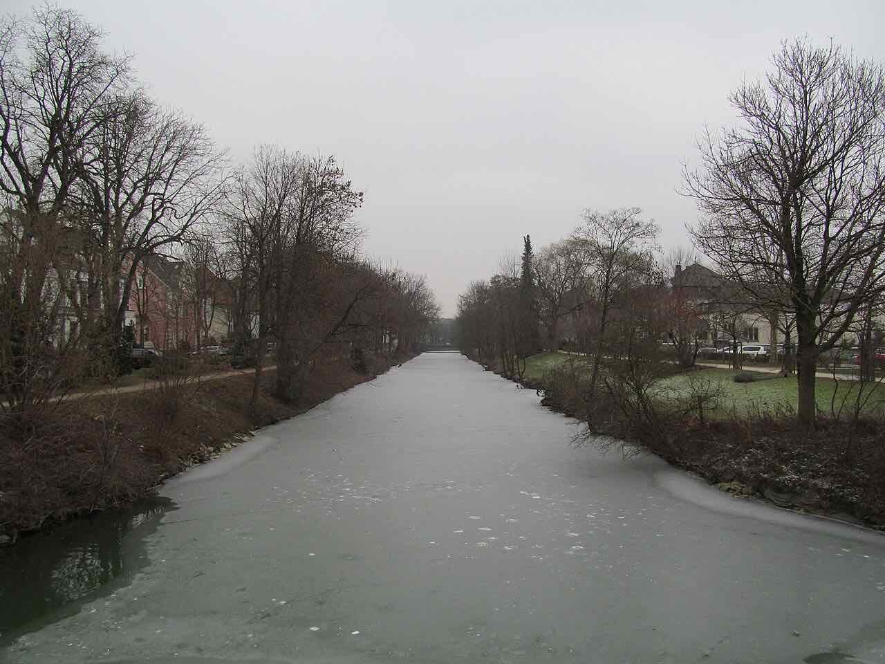 The straight Schifffahrtskanal in Lippstadt in winter, with a skin of ice on the water and bare trees and houses along both banks