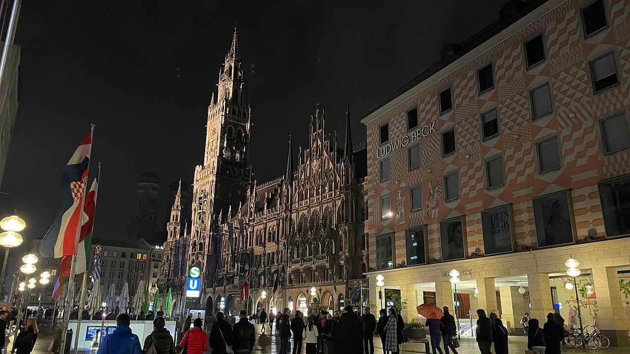 The Neues Rathaus at Marienplatz in Munich at night with people walking across the square