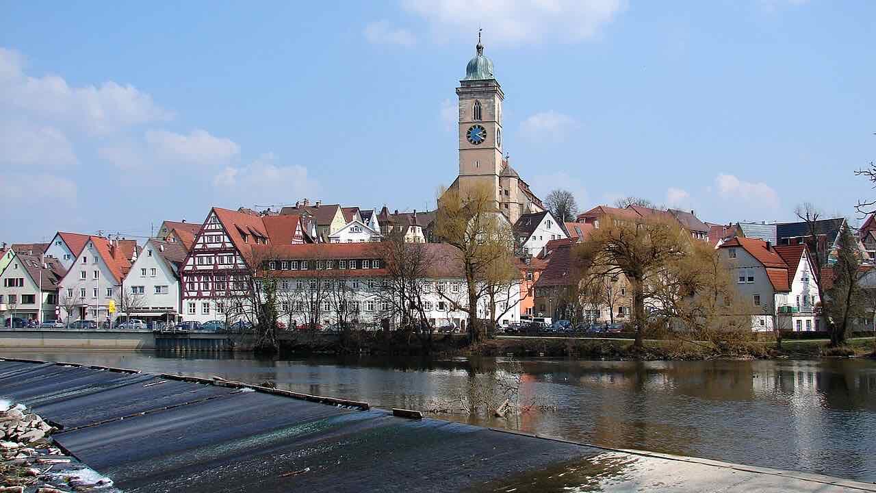 The old town of Nürtingen above the Neckar weir, with the clock tower of the Stadtkirche St. Laurentius behind half-timbered houses and willows