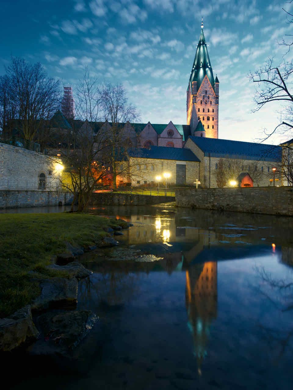 The spring basin of the Dielenpader with the Kaiserpfalz and the cathedral lit at dusk in Advent