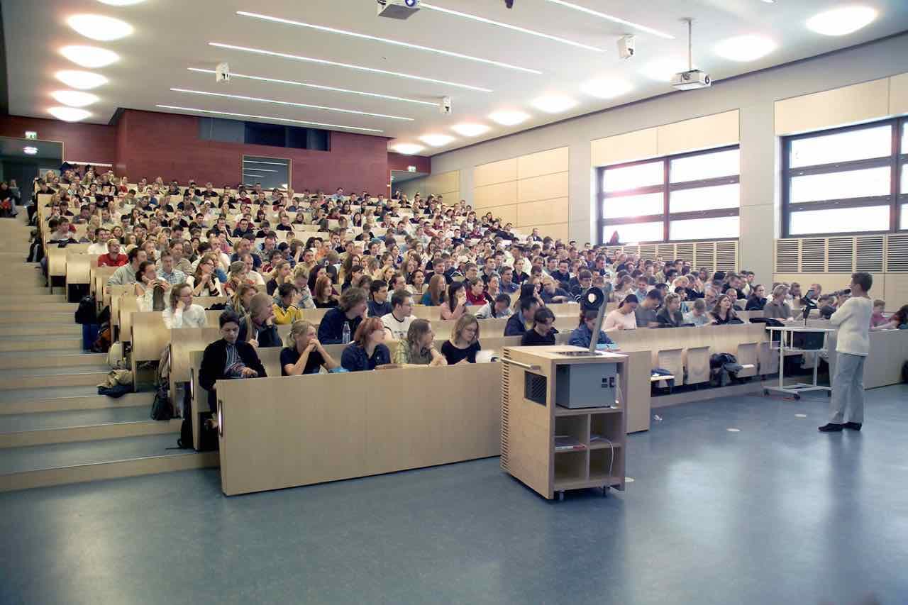 A full tiered lecture hall at the University of Rostock with a lecturer at the front