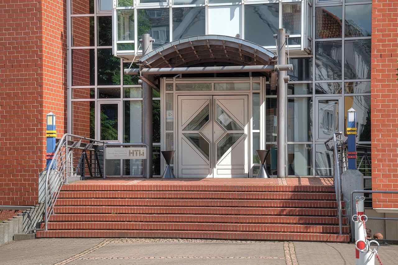 The brick and glass entrance of a htw saar building with a flight of red brick steps