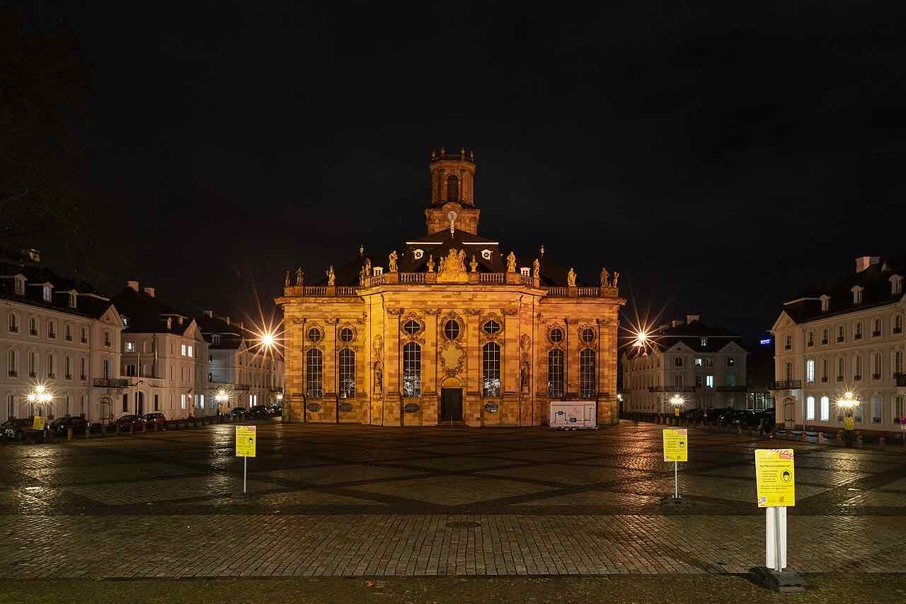 The baroque Ludwigskirche lit up at night on its paved square, with white town houses on both sides