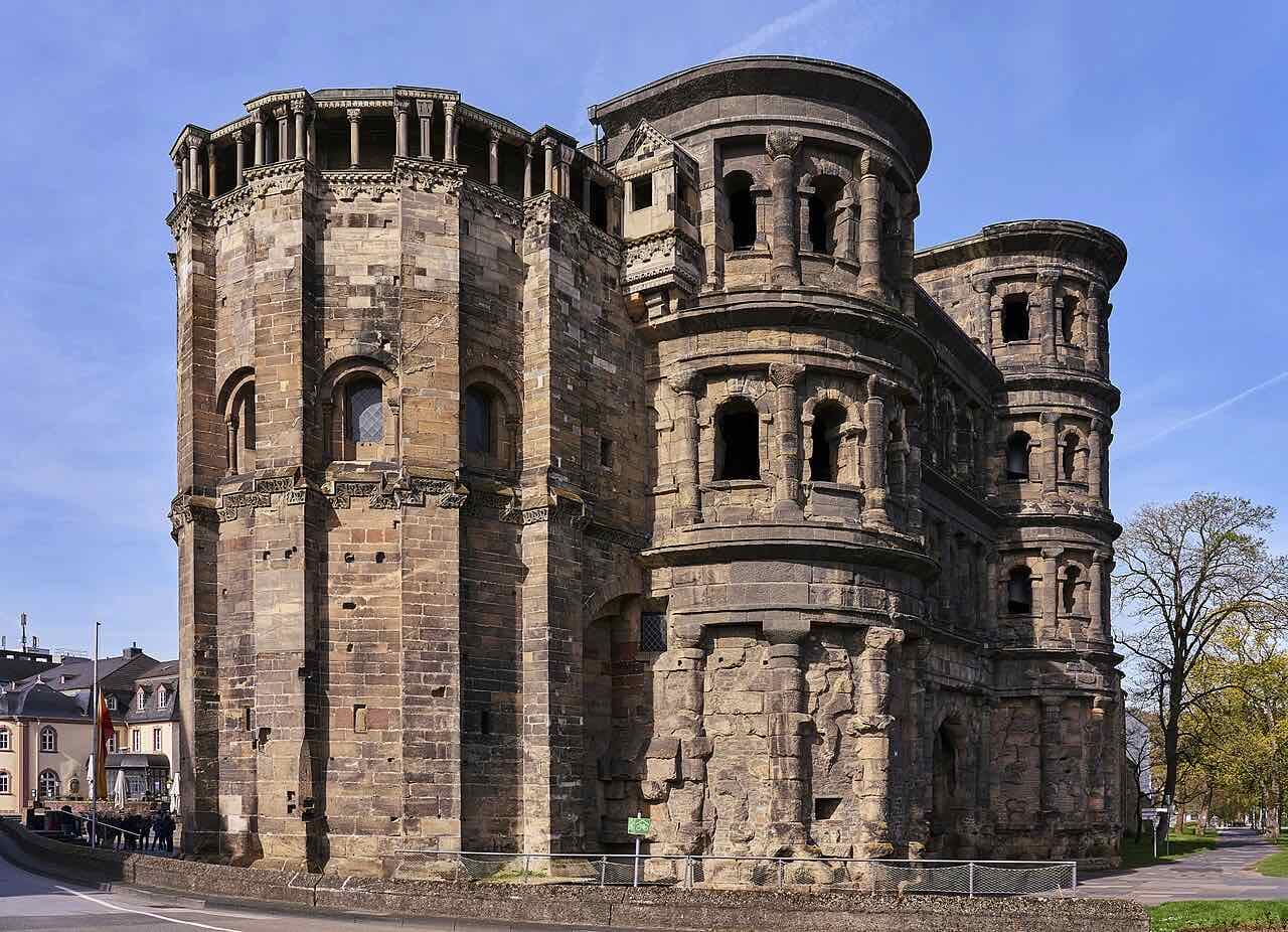 The Porta Nigra, the dark sandstone Roman city gate of Trier, seen from the side under a blue sky